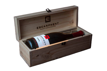 Wine bottle in a wooden box with 'Escarpment' branding on a white background