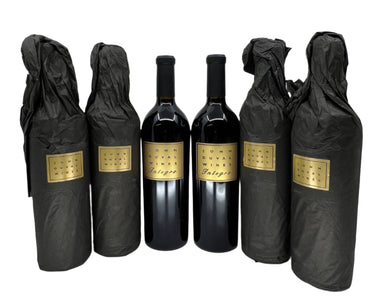 Five bottles of wine wrapped in black cloth with gold labels on a white background